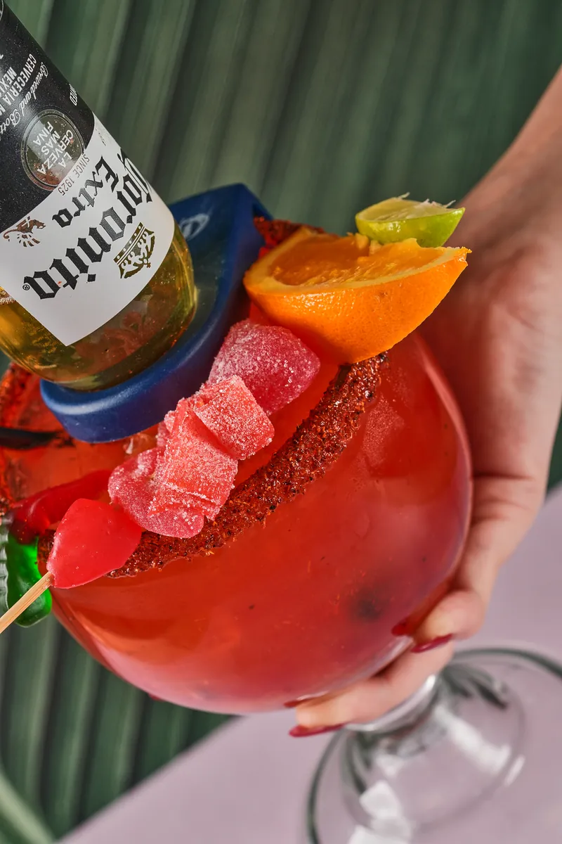 Michelada topped with a Corona and a skewer of fruit