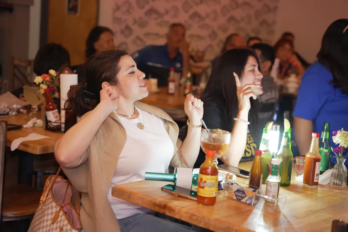 Two guests laughing over drinks and seafood
